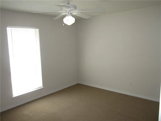 an empty room with a window and a fan