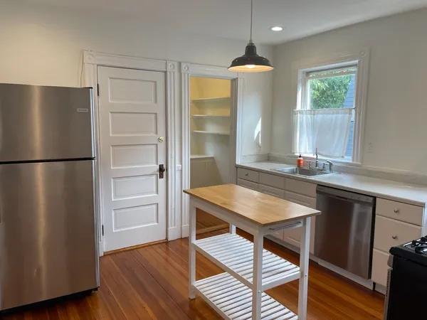 a kitchen with a refrigerator and wooden floor