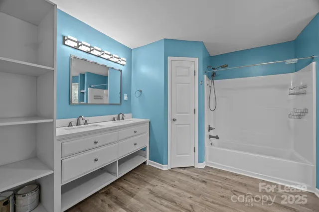 a bathroom with a double vanity sink mirror and bathtub