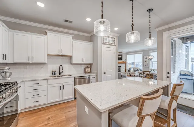 a kitchen with stainless steel appliances kitchen island granite countertop a stove a sink a center island a dining table and chairs