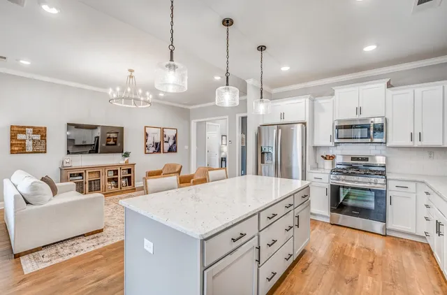 a large kitchen with kitchen island a stove a sink a center island a refrigerator wooden floor and living room view