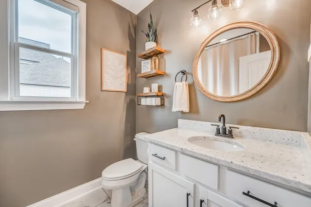 a bathroom with a granite countertop toilet a sink and a mirror
