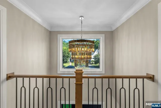 a hallway with wooden floor a chandelier and a window