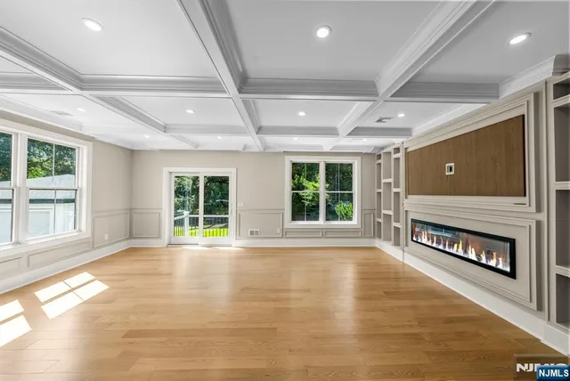 a view of an empty room with wooden floor fireplace and a window
