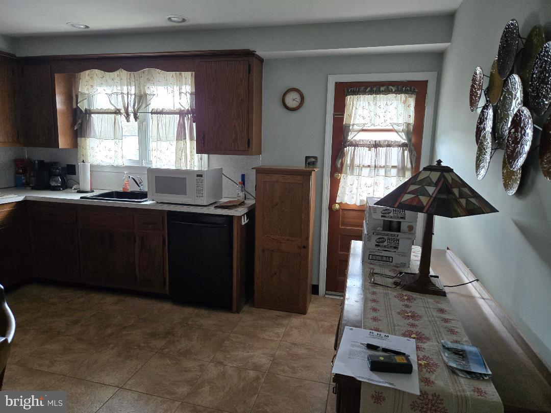 16 Lawnton Road Willow Grove, PA 19090 - Photo 3 of 9 a kitchen with stainless steel appliances granite countertop a refrigerator a sink dishwasher a stove a dining table and chairs with wooden floor