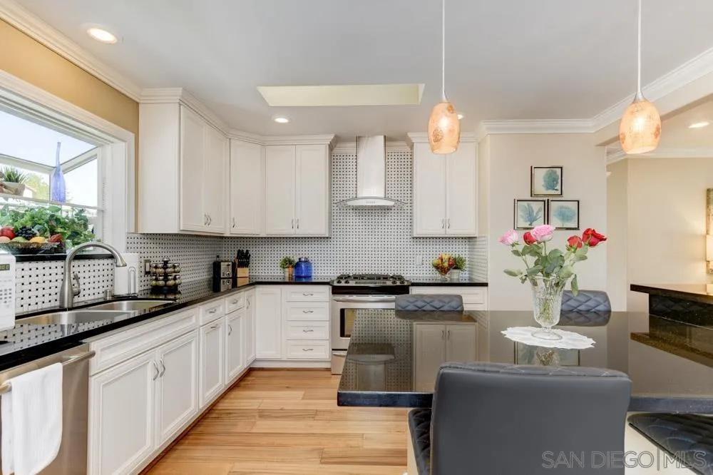 1221 4th Street Coronado, CA 92118 - Photo 16 of 24 a kitchen with granite countertop a stove a sink and white cabinets