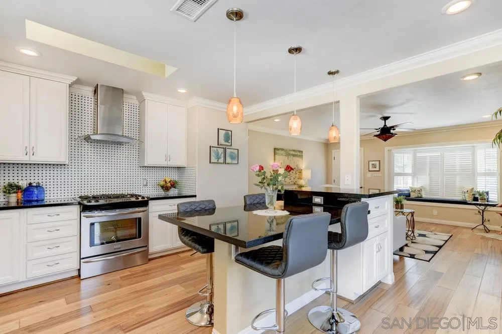 1221 4th Street Coronado, CA 92118 - Photo 17 of 24 a kitchen with stainless steel appliances a stove a sink dishwasher and white cabinets with wooden floor