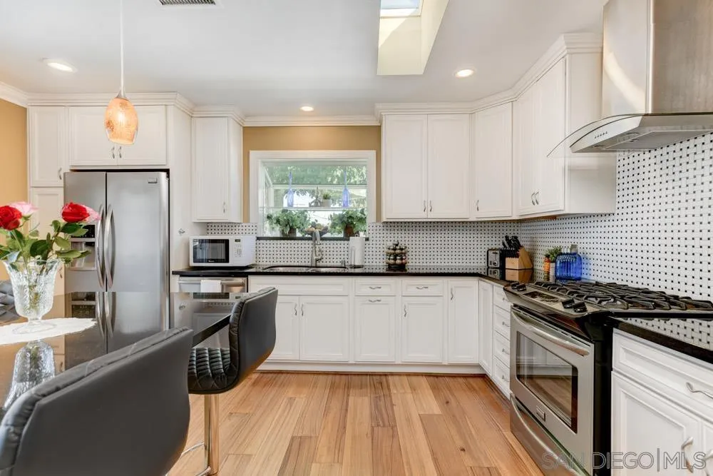 1221 4th Street Coronado, CA 92118 - Photo 18 of 24 a kitchen with granite countertop stainless steel appliances a sink cabinets and a window