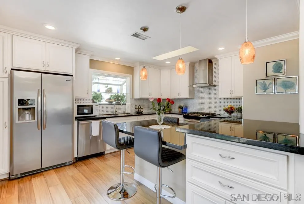 1221 4th Street Coronado, CA 92118 - Photo 4 of 24 a kitchen with stainless steel appliances granite countertop a stove a sink dishwasher a refrigerator white cabinets and wooden floor next to a window