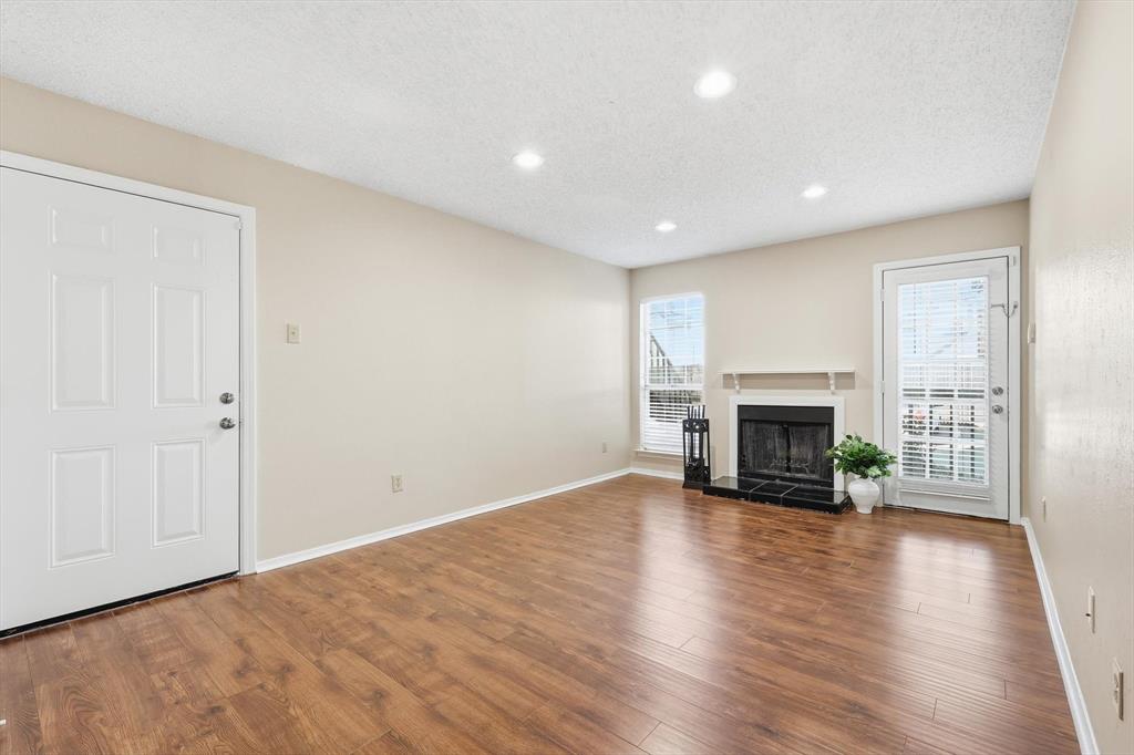 18333 Roehampton Drive, Unit 716 Dallas, TX 75252 - Photo 5 of 24 an empty room with wooden floor fireplace and windows