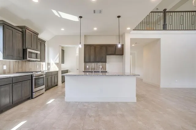 a large white kitchen with kitchen island a sink a stove a refrigerator and a oven