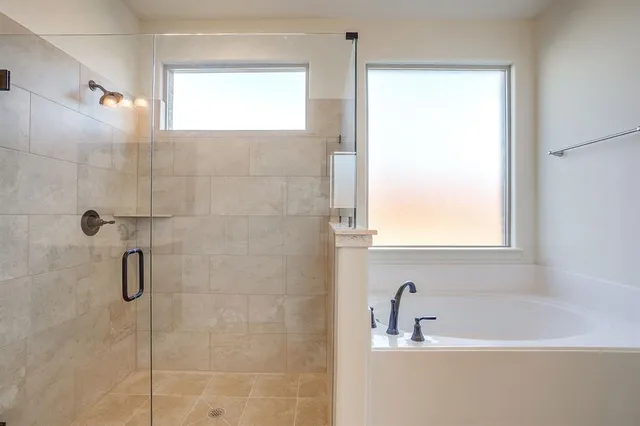 a bathroom with a bathtub a shower and a window