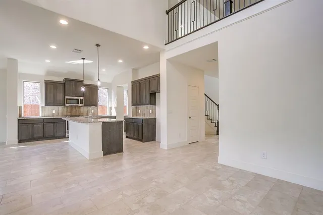 a view of kitchen with kitchen island granite countertop a refrigerator cabinets and a sink