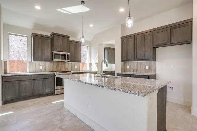 a large kitchen with granite countertop a sink a counter space appliances and cabinets
