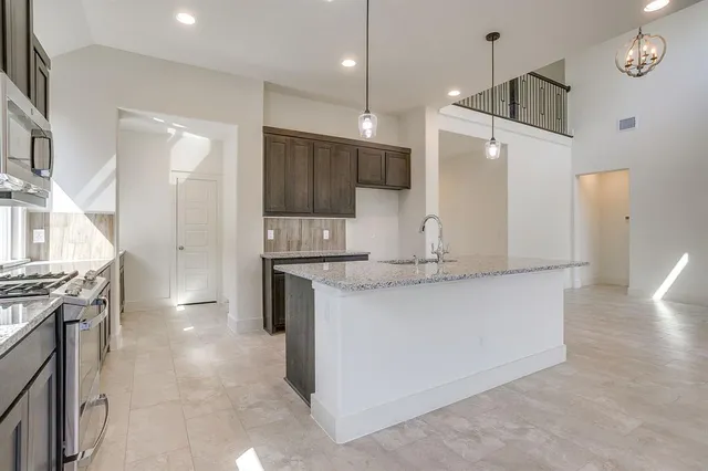 a kitchen with kitchen island a counter top space a sink stainless steel appliances and cabinets