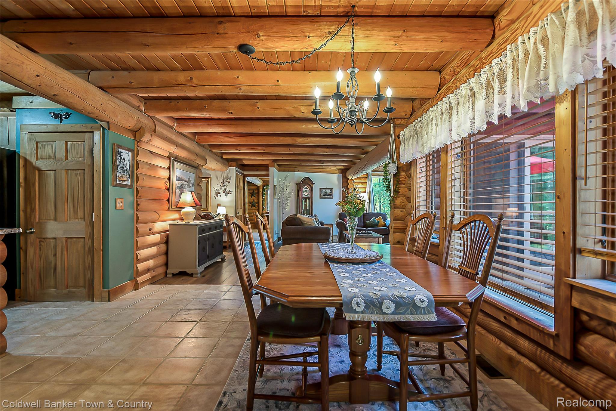 7023 Munsell Road Howell, MI 48843 - Photo 29 of 55 Log cabin interior featuring exposed wood beam ceilings, log walls, ceramic tile flooring, and multi-pane windows with wood blinds