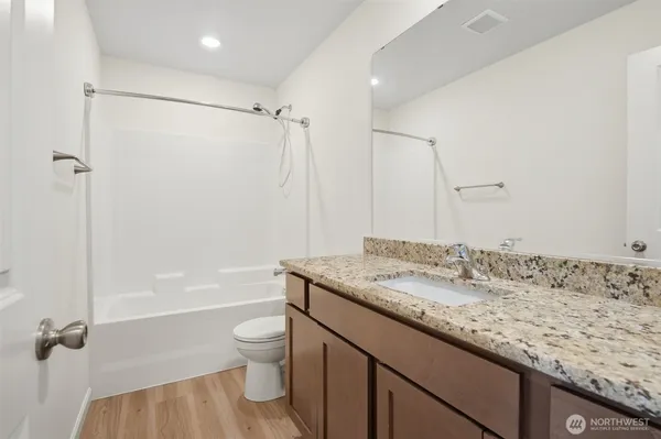 a bathroom with a granite countertop sink a toilet and shower