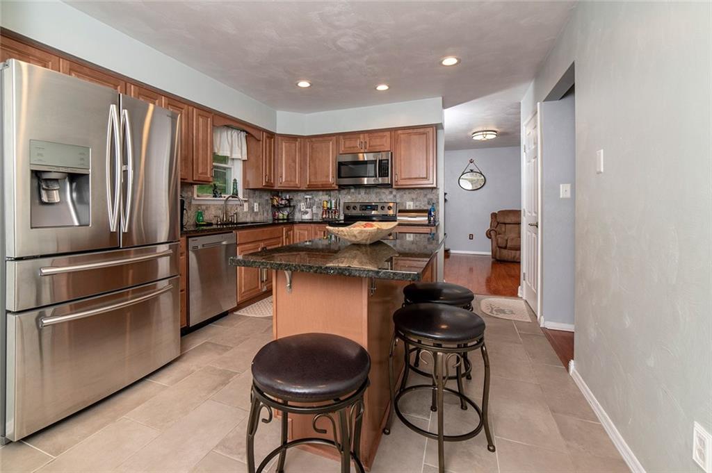 425 Marguerite Road Latrobe, PA 15650 - Photo 7 of 25 FEATURING CUSTOM HICKORY CABINETRY, TILE FLOOR, GREY STONE BACKSPLASH, GRANITE COUNTERS, CENTER ISLAND AND STAINLESS SAMSUNG APPLIANCES.