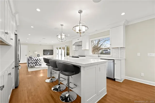 a kitchen with a center island wooden floor stainless steel appliances and dining table