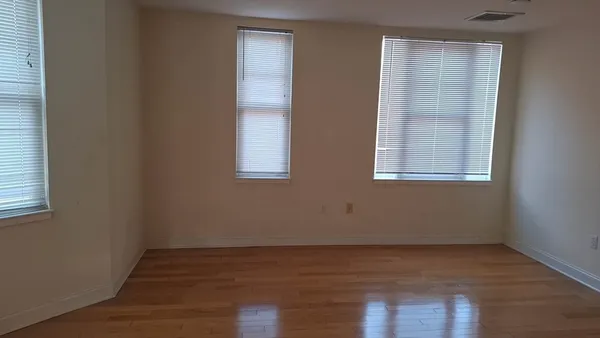 an empty room with wooden floor and windows