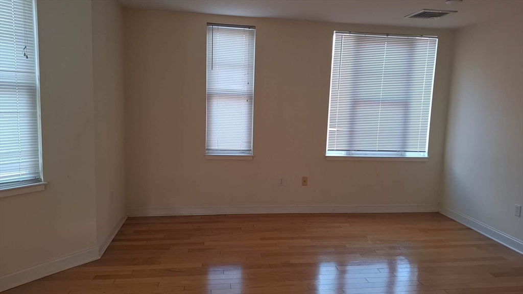 4048 Washington Street, Unit 5 Boston, MA 02131 - Photo 2 of 9 an empty room with wooden floor and windows
