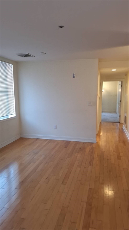 4048 Washington Street, Unit 5 Boston, MA 02131 - Photo 4 of 9 an empty room with wooden floor and windows
