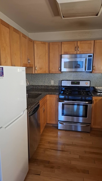 4048 Washington Street, Unit 5 Boston, MA 02131 - Photo 5 of 9 a kitchen with granite countertop a stove and a refrigerator
