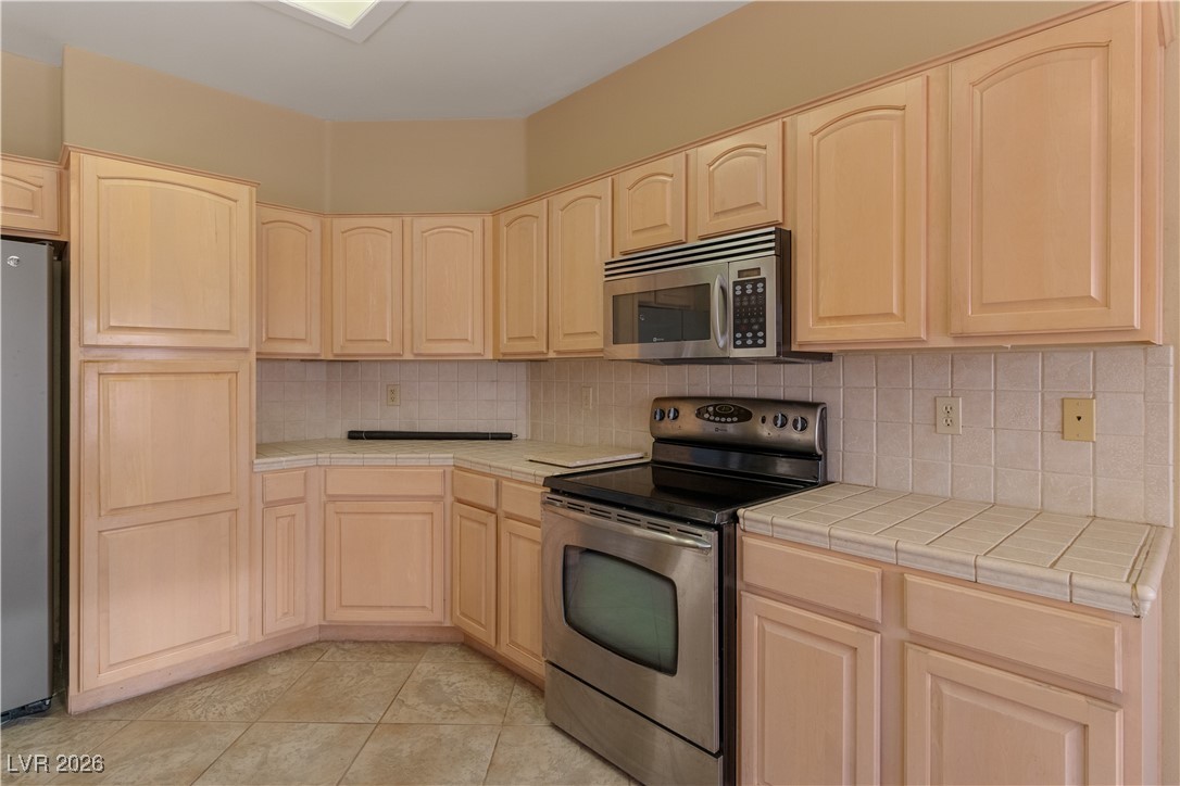 1210 Country Club Drive Laughlin, NV 89029 - Photo 12 of 80 Kitchen featuring tile counters, stainless steel appliances, tasteful backsplash, and light brown cabinetry