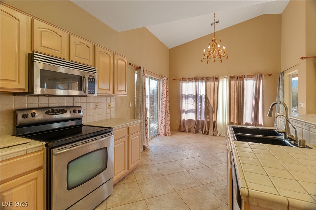 1210 Country Club Drive Laughlin, NV 89029 - Photo 13 of 80 Kitchen with tile counters, appliances with stainless steel finishes, high vaulted ceiling, decorative light fixtures, and backsplash