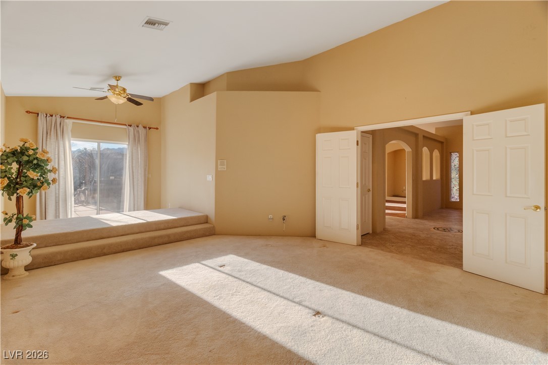 1210 Country Club Drive Laughlin, NV 89029 - Photo 17 of 80 Primary bedroom with lofted ceiling, carpet flooring, bedside lights, sliding glass door to back patio, and a ceiling fan