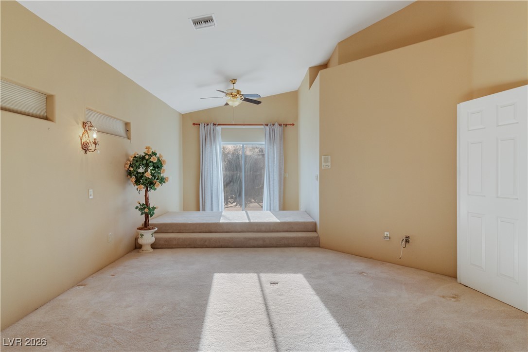 1210 Country Club Drive Laughlin, NV 89029 - Photo 18 of 80 Primary bedroom with lofted ceiling, carpet flooring, bedside lights, sliding glass door to back patio, and a ceiling fan