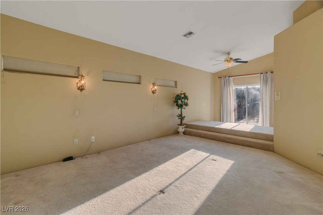 1210 Country Club Drive Laughlin, NV 89029 - Photo 19 of 80 Primary bedroom with lofted ceiling, carpet flooring, bedside lights, sliding glass door to back patio, and a ceiling fan