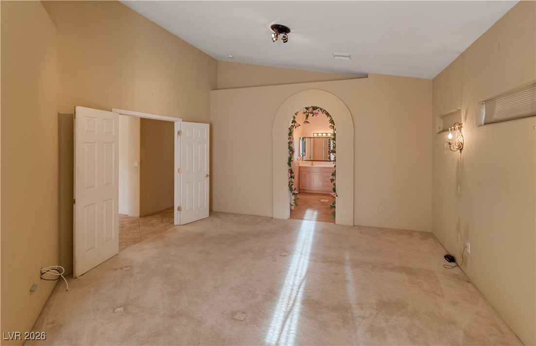 1210 Country Club Drive Laughlin, NV 89029 - Photo 20 of 80 Primary bedroom with arched walkway into Ensuite Bathroom and lofted ceiling