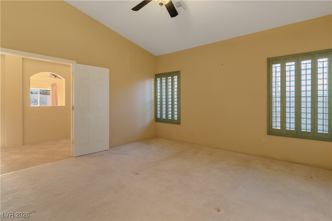 1210 Country Club Drive Laughlin, NV 89029 - Photo 27 of 80 Second Suite Bedroom with dual doors, lofted ceiling, multiple windows with shutters, a ceiling fan, and carpet