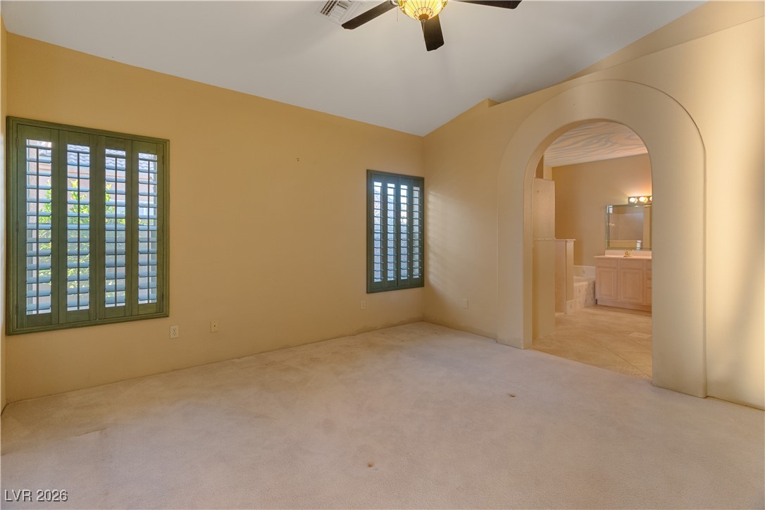 1210 Country Club Drive Laughlin, NV 89029 - Photo 28 of 80 Second Suite Bedroom with dual doors, lofted ceiling, multiple windows with shutters, a ceiling fan, and carpet