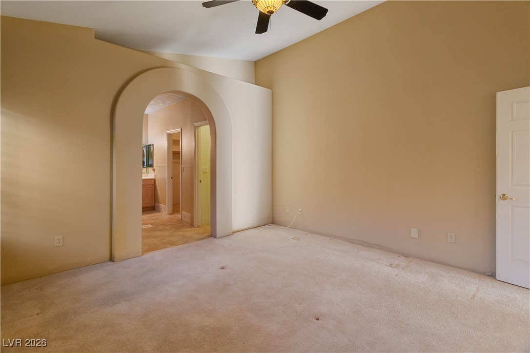 1210 Country Club Drive Laughlin, NV 89029 - Photo 29 of 80 Carpeted Second Suite bedroom featuring arched walkways into Ensuite Bathroom and a ceiling fan