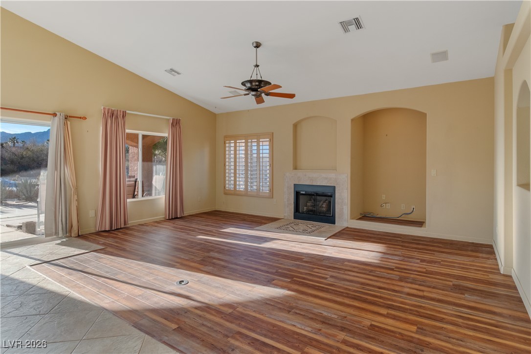 1210 Country Club Drive Laughlin, NV 89029 - Photo 3 of 80 Unfurnished living room featuring a tiled fireplace, light wood-style floors, lofted ceiling, and ceiling fan