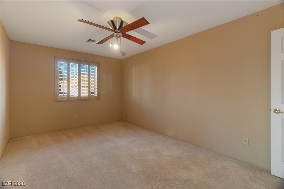1210 Country Club Drive Laughlin, NV 89029 - Photo 39 of 80 Third bedroom featuring a ceiling fan, carpet, and door access to the front exterior of the home, perfect for guest entry or a home office