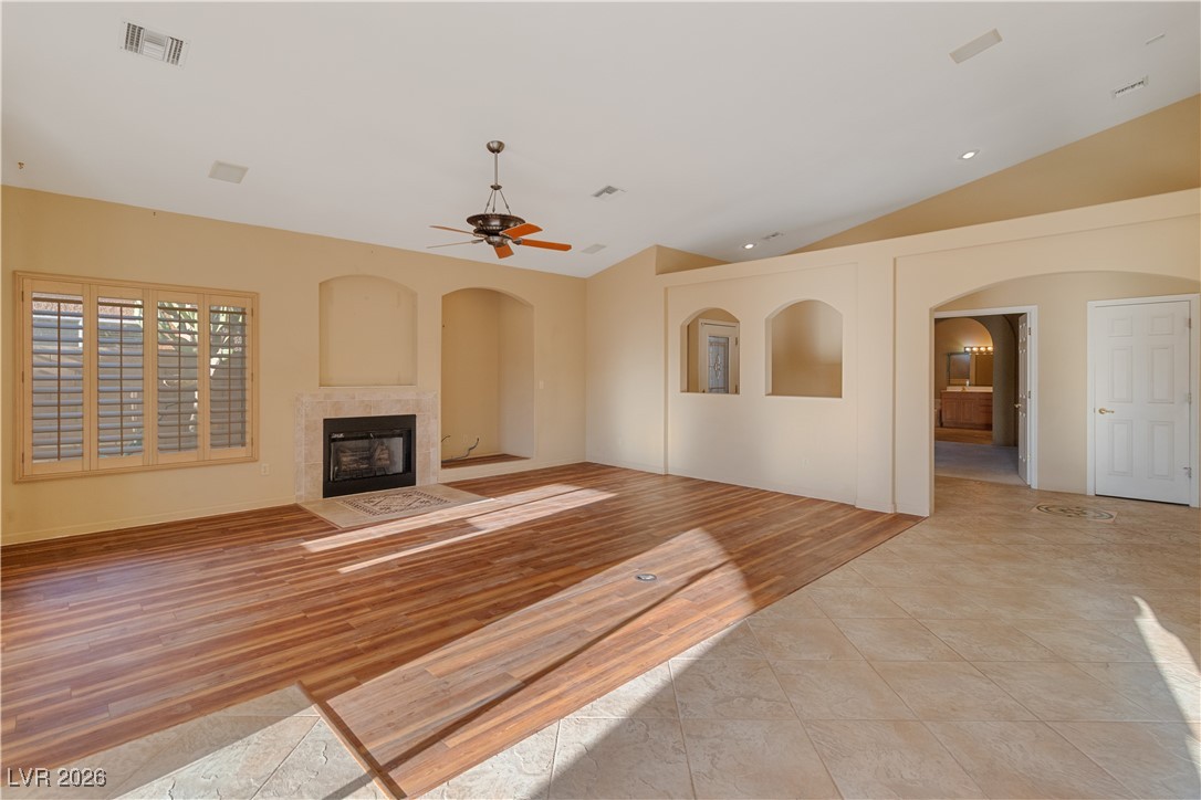 1210 Country Club Drive Laughlin, NV 89029 - Photo 4 of 80 Unfurnished living room with arched walkways, lofted ceiling, a tile fireplace, light wood-type flooring, and a ceiling fan