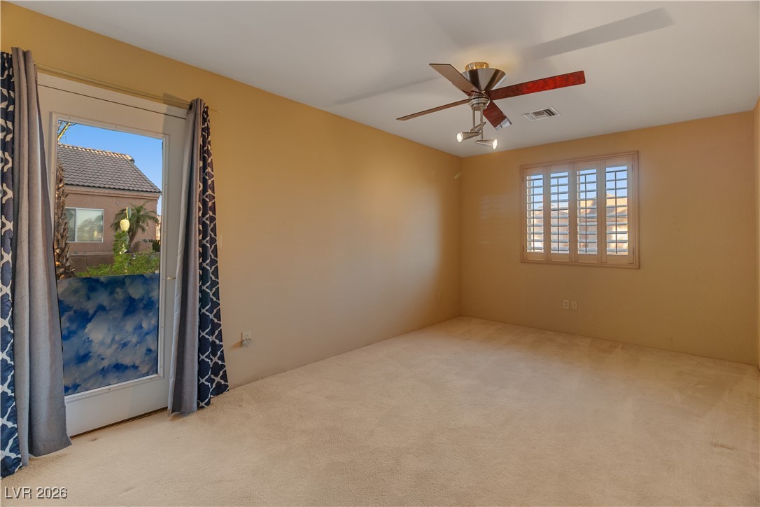1210 Country Club Drive Laughlin, NV 89029 - Photo 41 of 80 Carpeted Third bedroom with plenty of natural light featuring a ceiling fan, carpet, and door access to the front exterior of the home, perfect for guest entry or a home office