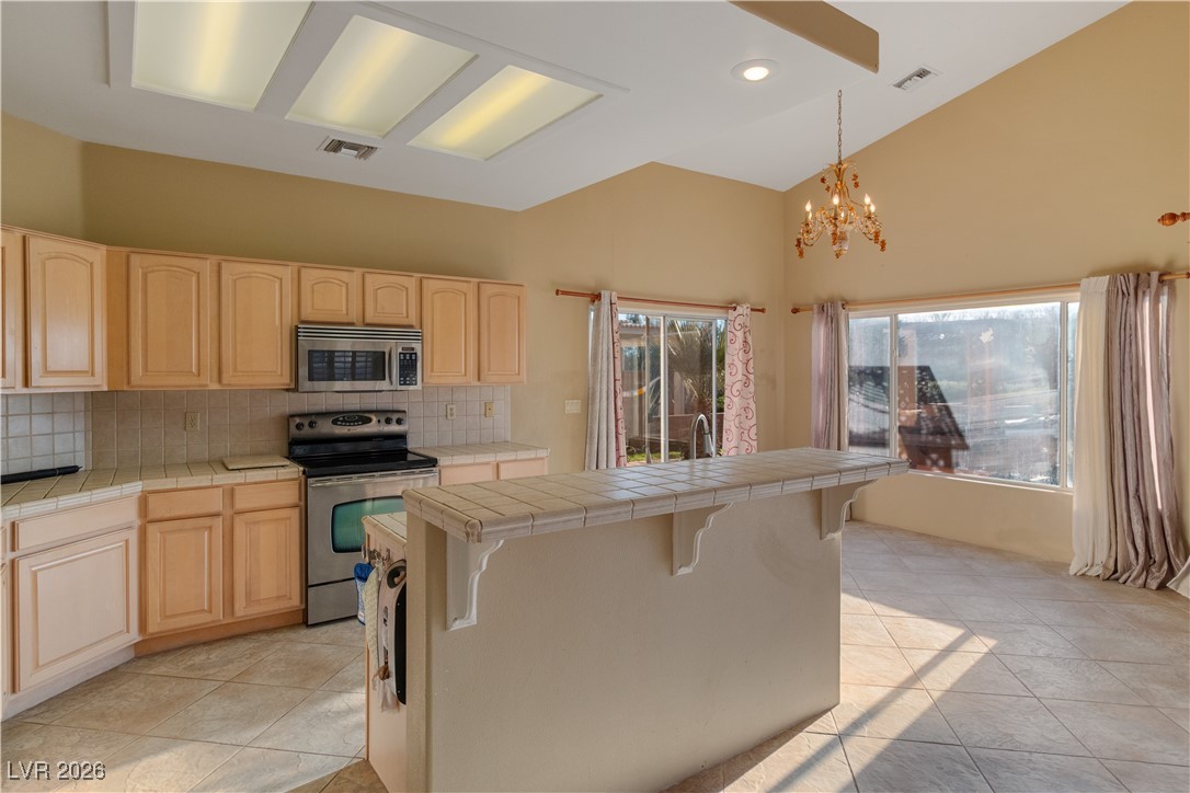 1210 Country Club Drive Laughlin, NV 89029 - Photo 7 of 80 Kitchen with tile countertops, pendant lighting, stainless steel appliances, light brown cabinets, and high vaulted ceiling