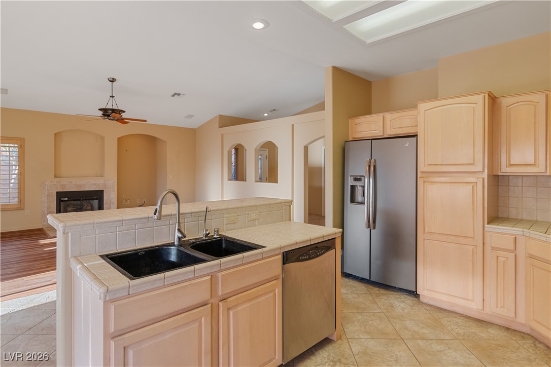 1210 Country Club Drive Laughlin, NV 89029 - Photo 10 of 80 Kitchen with tile counters, light brown cabinets, appliances with stainless steel finishes, a tiled fireplace, and a ceiling fan