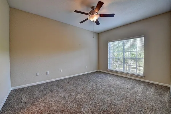 an empty room with windows and fan