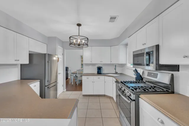 a kitchen with stainless steel appliances granite countertop a sink a stove a refrigerator cabinets and chairs