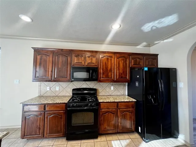 a kitchen with granite countertop a refrigerator stove and microwave