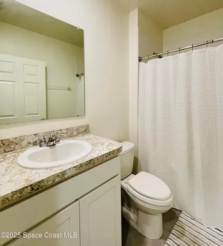 a bathroom with a granite countertop sink toilet and a mirror