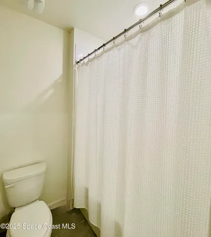 a white toilet sitting next to a shower curtain