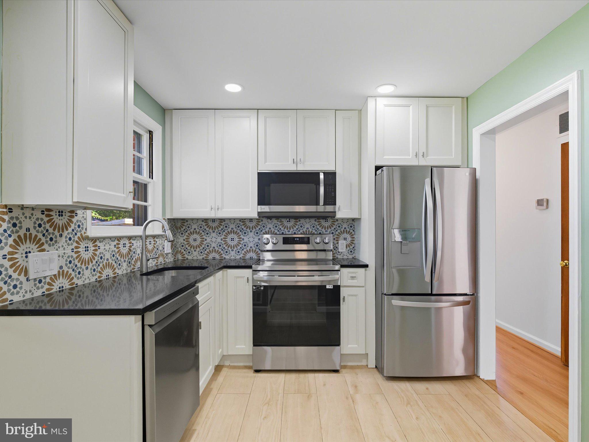 12907 Matey Road Silver Spring, MD 20906 - Photo 11 of 45 a kitchen with granite countertop a refrigerator stove and wooden floor