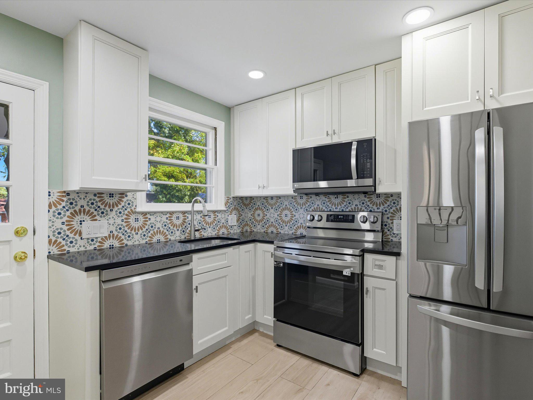 12907 Matey Road Silver Spring, MD 20906 - Photo 12 of 45 a kitchen with stainless steel appliances granite countertop a stove a refrigerator and a microwave