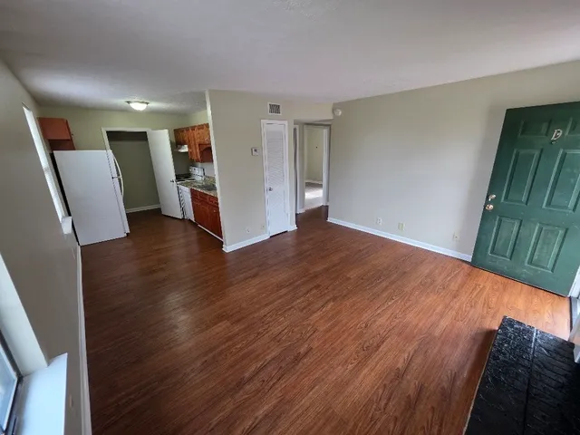 a view of an empty room with wooden floor and a sink